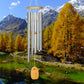 Campana de viento, tubos de metal y madera, montaña nevada con río y bosque de otoño